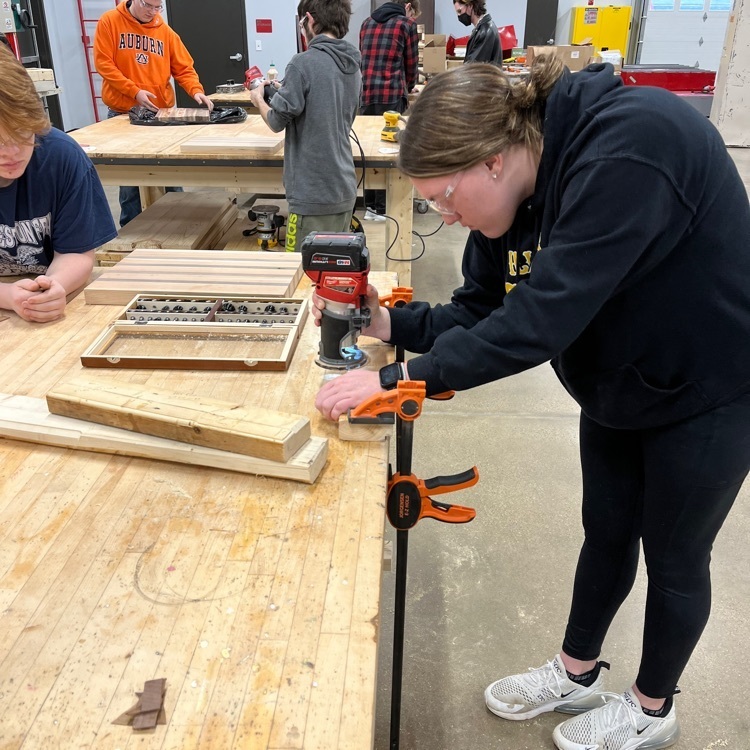 Karah practices using a router while Koltan observes. A router is used to put a decorative edge on the cutting board.